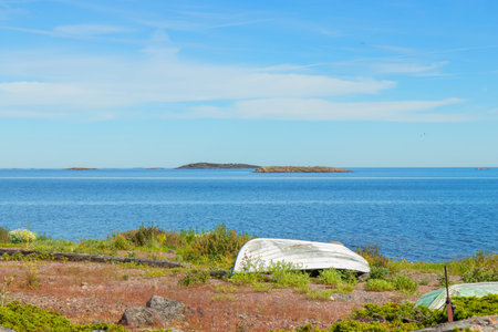 Boat on the shore of the Baltic Sea. Calm coastal scene with natural coastline, rocks and water, evoking tranquility, northern landscape, and maritime lifestyleの写真素材