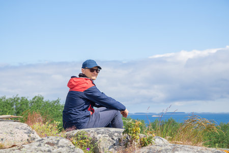 Young man sitting and resting during a hike in Finnish nature. Highlights outdoor adventure,...