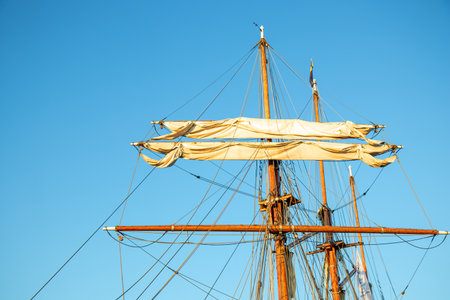 Furled sails on a vintage sailboat. Calm harbor scene with traditional wooden vessel, peaceful maritime atmosphere, and northern coastal charmの写真素材