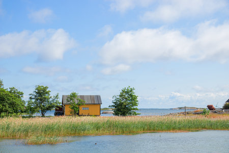 Beautiful view of wooden boat sheds on the water of the Baltic Sea in a cozy fishing Finnish village. Traditional Nordic architecture and peaceful coastal lifestyleの写真素材