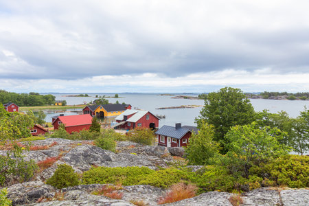 Scenic view of a Finnish fishing village by the sea. Traditional wooden houses, boathouses, piers, and peaceful coastal landscape in northern countrysideの写真素材