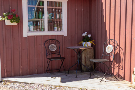 Small table and two chairs on the terrace of a rustic country house. Cozy outdoor space for rest, summer relaxation, and connection with simple rural lifestyleの写真素材