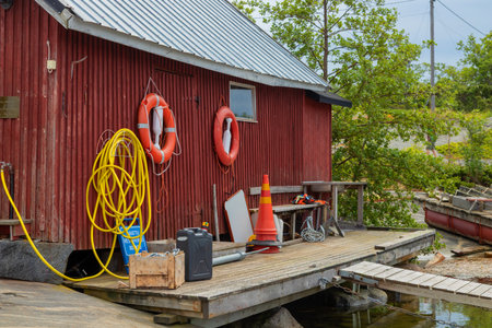 A rustic wooden boathouse with weathered walls, featuring a hanging hose, lifebelts and various tools neatly arranged, Baltic sea, Finlandの写真素材
