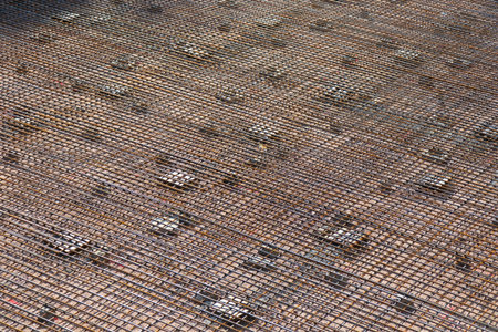 A prepared surface at a construction site with a metal rebar grid laid crosswise, ready for concrete...