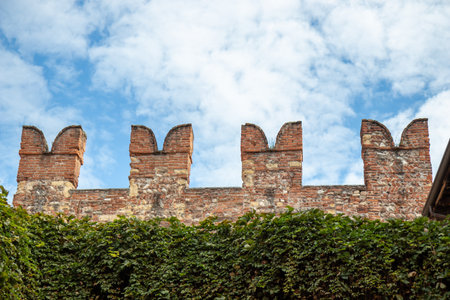 Swallowtail battlements or merlons and red brickwork of Castelvecchio, a medieval castle in Verona, Italy, showcasing fortified architecture and the historic military heritageの写真素材