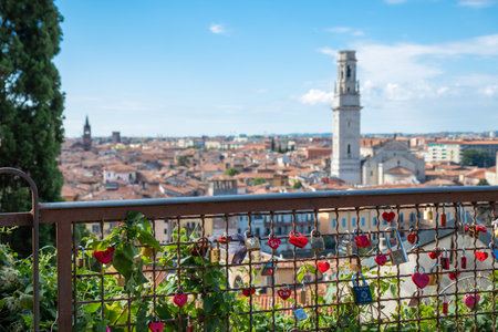 Romantic love locks from tourists in Verona with a view of Duomo di Verona, Cattedrale di Santa Maria Matricolare on the background, red-tiled roofs, medieval streets, and the charming Veneto skylineの写真素材