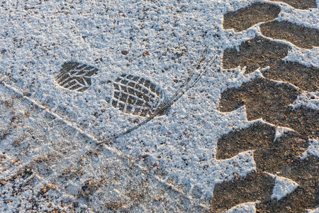 Footprints and tracks left on freshly fallen light snow. Soft, untouched snow surface showing human...