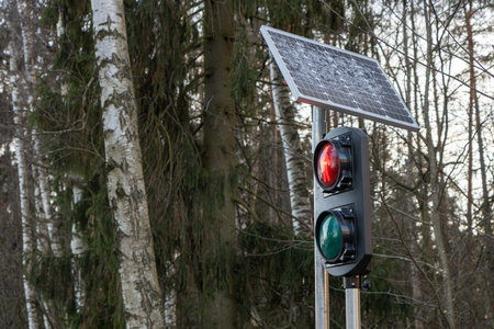 Traffic light mounted on a pole powered by solar panels. Outdoor road safety device using renewable energy in an urban or suburban environmentの写真素材