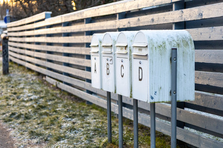Outdoor mailboxes placed along the street between neighboring residential houses. Metal post boxes used for daily postal delivery in a suburban areaの写真素材