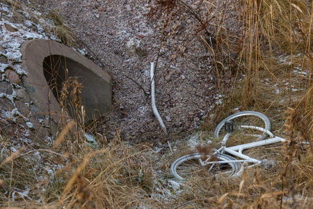 An abandoned bicycle found in a ditch. The damaged bike lies in grass and mud, showing signs of vandalism and neglect in an outdoor environment, Finland, Espooの写真素材