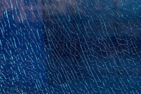 Blue shattered glass completely covered with cracks, creating a fragmented, textured surface with sharp patterns and a dramatic visual effectの写真素材