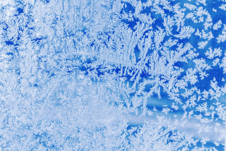 Close-up pattern of intricate frost patterns on a windowpane. Delicate crystalline ice formations,...