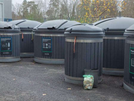 A line of large, semi-underground waste collection bins stand in a paved outdoor area, signifying a...