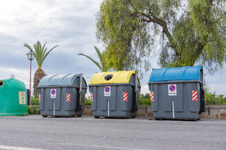 Color-coded waste and recycling bins in Spain help residents sort household waste. Yellow lids are...