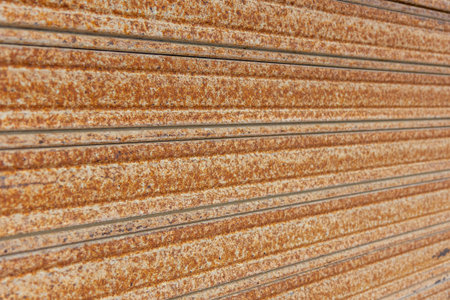 Close-up of a rusted corrugated metal surface with heavy oxidation, showing brown and orange...