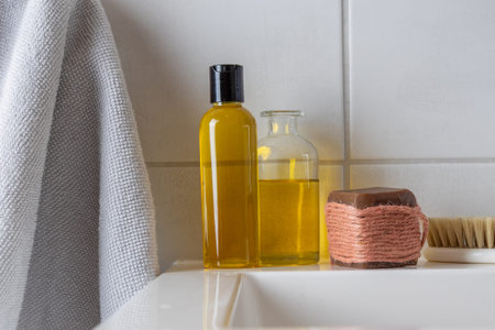 Natural bathing essentials including golden oils, a bar of soap wrapped in twine, and a bristle...