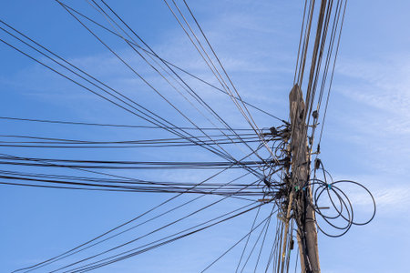 Low angle view of a utility pole with numerous power and communication lines stretching across a...