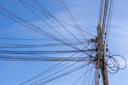 Low angle view of a utility pole with numerous power and communication lines stretching across a...