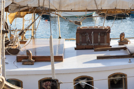 A wooden chest rests on the deck of a ship in Cartagena, Spain, with the sea and historic maritime...