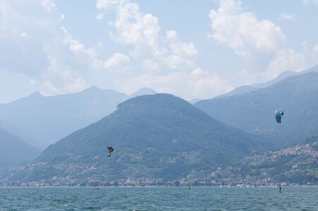 Lake Como, Italy - July 21, 2019. Water sport: kitesurfer is making a trick in the air on a bright...