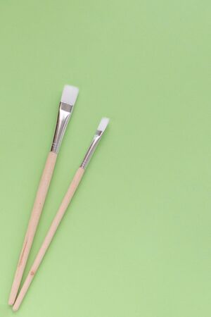 Back to school, minimalism concept. School supplies. Brushes for painting on pastel trendy green...