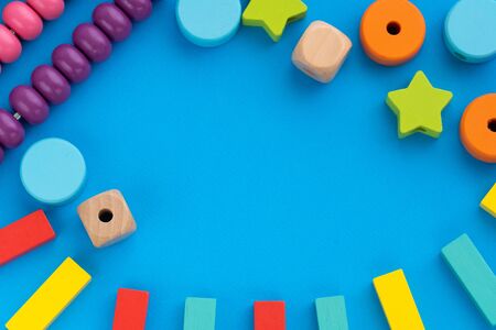 Top view on childrens educational games, frame from multicolored kids toys on blue paper background. Wooden bricks, cubes, stars, circles, scores. Flat lay, copy space for textの写真素材