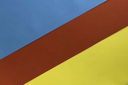 Yelllow blue red colored paper background. Geometric figures, shapes, lines. Abstract geometric flat composition. Empty space on multicolored cardboard. Card board background. Diagonal direction.の写真素材