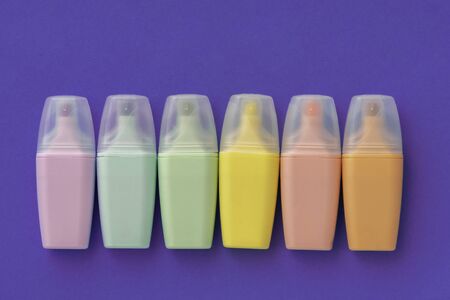 Highlighters set on colored violet background. Collection of markers different color. Flat lay, top view. Back to school, education concept.の写真素材