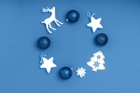 New Year and Christmas composition. Wreath from blue balls, white stars, chrismas tree on blue paper background. Top view, flat lay, copy space. Trendy color of the year 2020.の写真素材