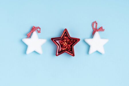 New Year and Christmas composition from white and red stars on pastel blue paper background. Top...