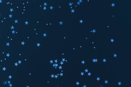 Sparkling stars glitter confetti on blue background. Classic festive christmas backdrop. Holiday new year backdrop. Trendy color 2020. Greeting card template.の写真素材