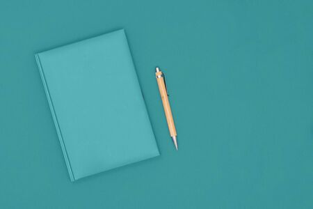 Top view of closed mint cover notebook with pen on mint desk background. Business concept. Top view, flat lay, copy space.の写真素材