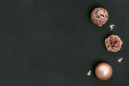 New Year and Christmas greeting card. Golden Christmas decorations, shiny balls, pine cones on black...