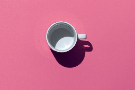Empty tea cup on pink paper background. Coffee mug. Minimal concept Hard deep shadow. Flat lay, top viewの写真素材