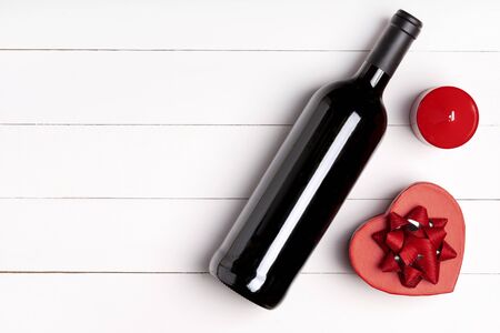 Heart, candle, wine bottle on white wooden surface. Valentine's day concept. Flat lay, top view, from above, copy spaceの写真素材