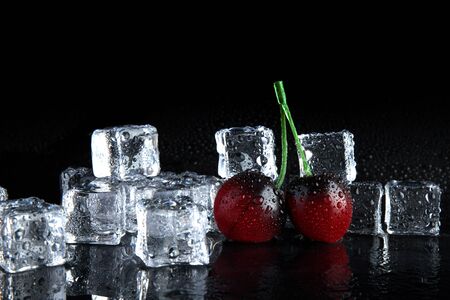 golden cherry frozen in ice on black backgroundの写真素材