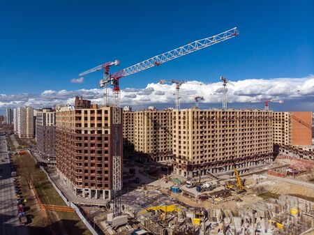 Construction site background. Hoisting cranes and new multi-storey buildings. Industrial background.の写真素材