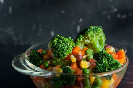 healthy food steamed vegetables on plate at dark backgroundの写真素材