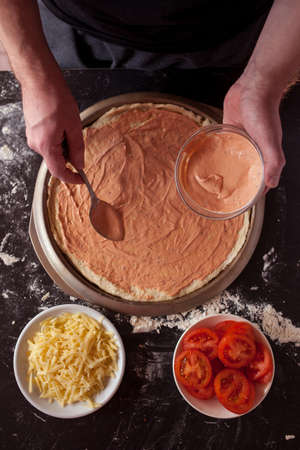 Food concept. Fresh original Italian raw pizza, preparation in traditional style. Making pizza at home. Pizza cooking in a real home interiorの写真素材