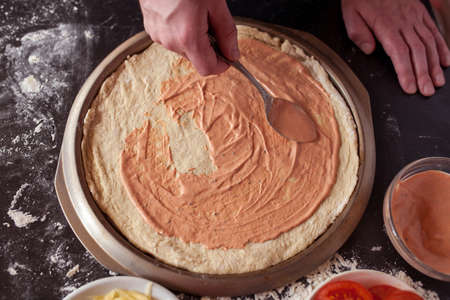 Food concept. Fresh original Italian raw pizza, preparation in traditional style. Making pizza at home. Pizza cooking in a real home interiorの写真素材