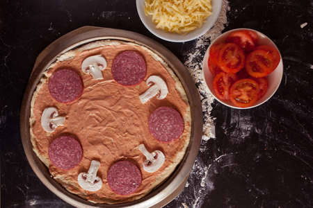 Food concept. Fresh original Italian raw pizza, preparation in traditional style. Making pizza at home. Pizza cooking in a real home interiorの写真素材