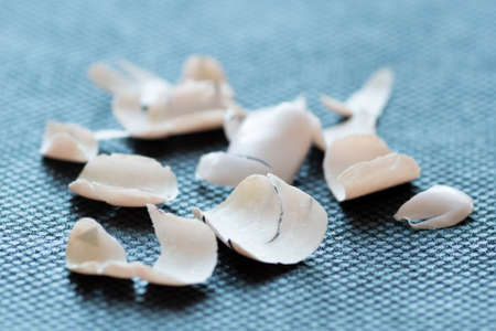 Close-up of gel polish after removal from nails, broken pieces of fake Acrylic nails collection on dark black background.の写真素材