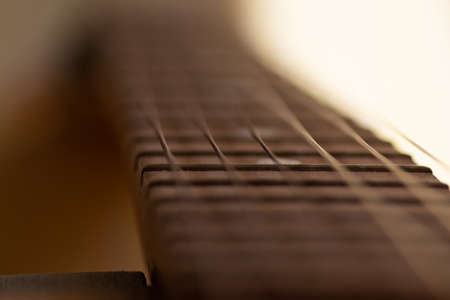 Closeup detail of steel guitar strings and frets for making music. Guitar neck in selective focus.