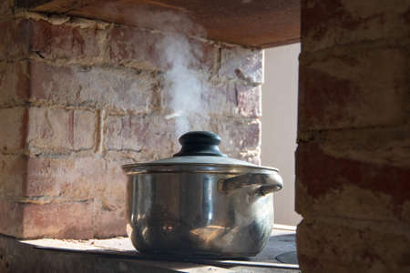 old pan on a Russian brick stove, steam from a crutch.
