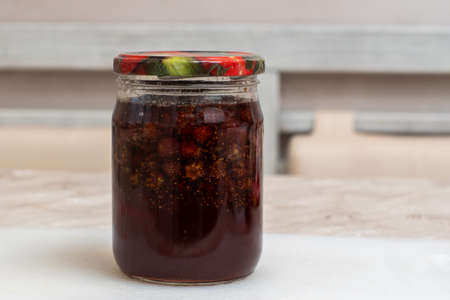 Homemade strawberry jam in a glass jar with a colored lid on the table. The concept of a healthy diet, home cooking meal.の写真素材