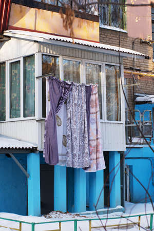 multi-colored bedding hanging from a balcony or clothesline in a blue rural house made of wood and stone.の写真素材