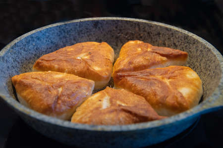 gray plate with delicious fried pies on a black background, isolate.の写真素材