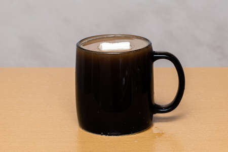 Close-up big cup of coffee mug with marshmallows on brown table on gray background.の写真素材