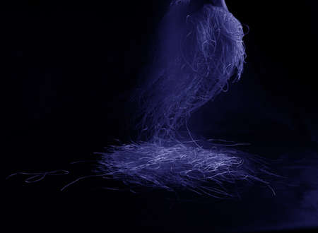 blue, purple tangled threads hang and fall on a black background. Suitable as weaving, cleaning or abstract background.の写真素材