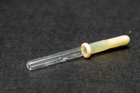glass dropper with a yellow rubber tip on a black background close-up.の写真素材